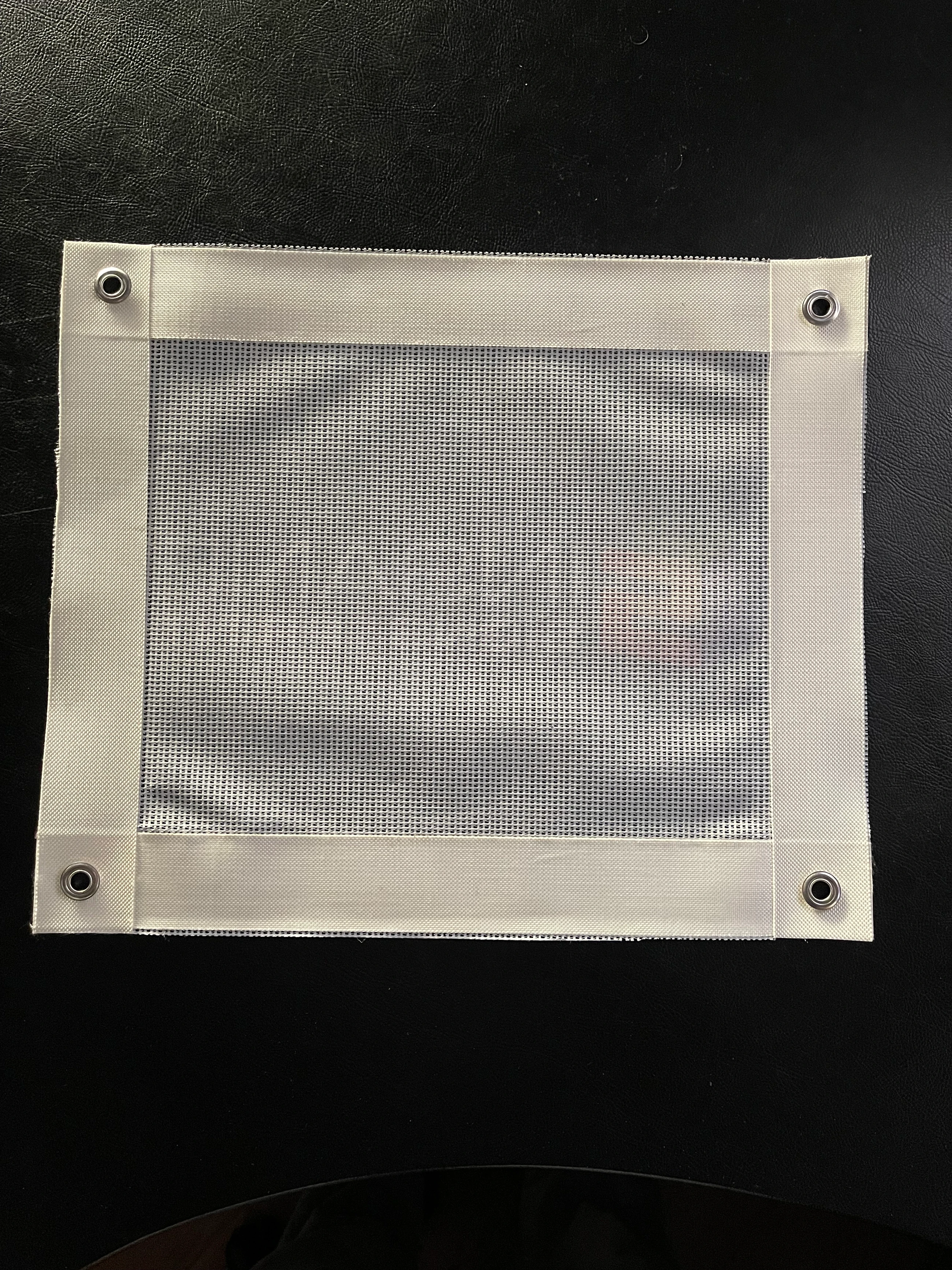 Back of a printed mesh banner showing the 50mm welded edge and stainless steel eyelets